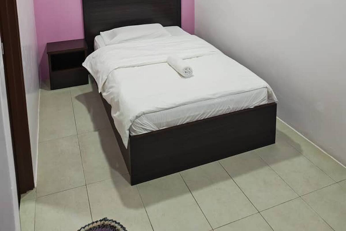 A bedroom with a bed, a nightstand, a wall-mounted air conditioner, and a ceiling light.