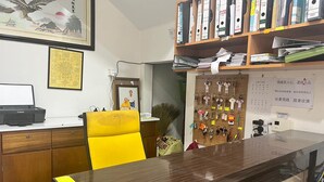 A reception desk with a wooden counter, a Canon printer, a yellow chair, and a wall-mounted key rack.