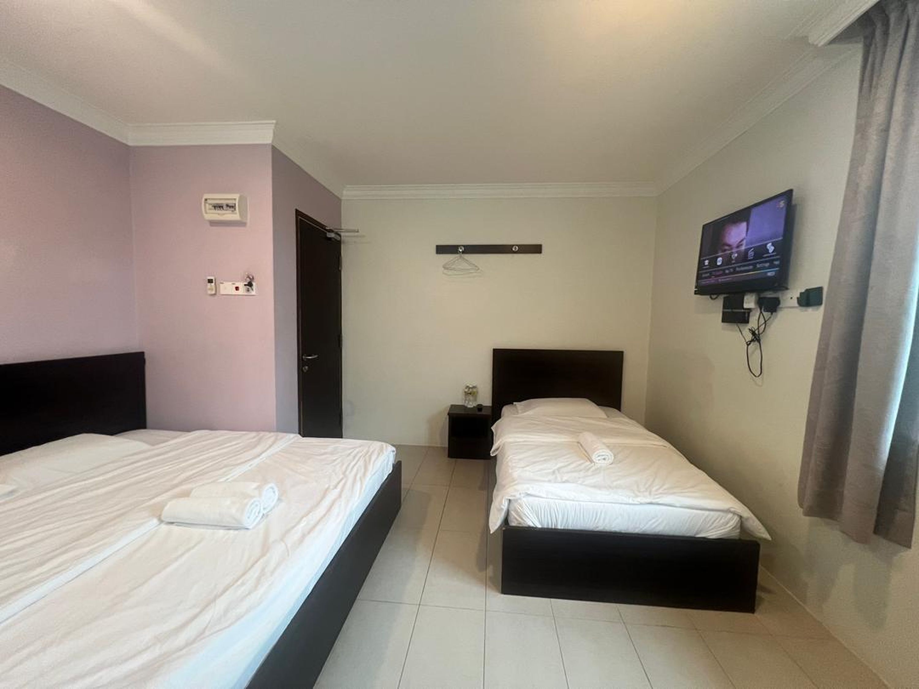 Habitación de hotel con dos camas, televisión, una mesita y una puerta.