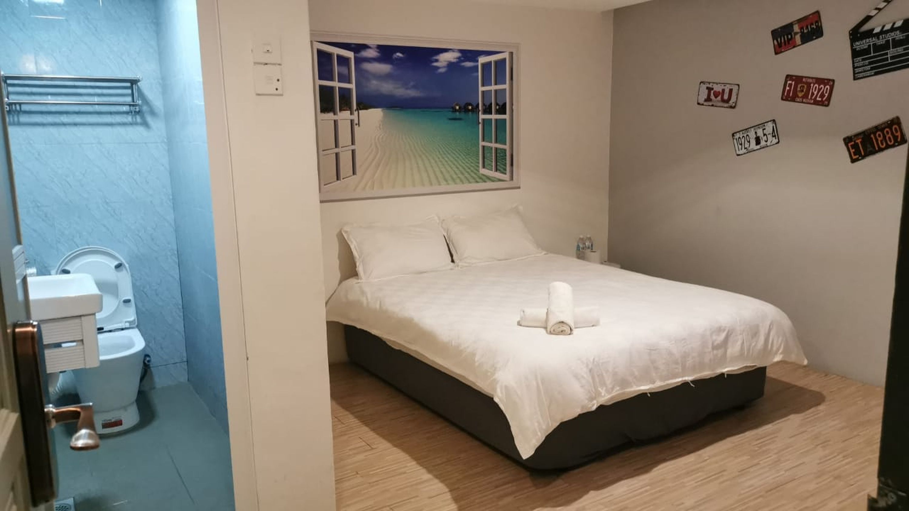 A bedroom with a bed, a bathroom with a toilet, and a wall with movie clapperboards.