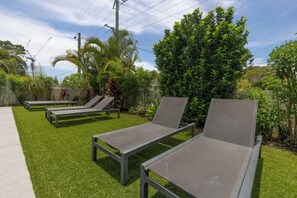 Un jardín con tres sillones de jardín y una pequeña palmera.