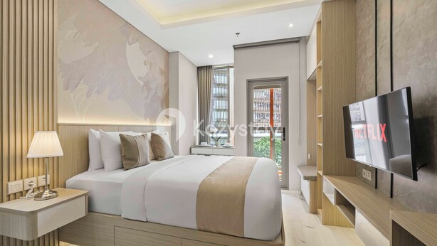 Una habitación de hotel moderna con una cama grande, un televisor, una mesita de noche y una obra de arte colgada en la pared.