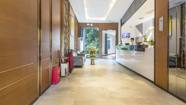 Zona de recepción de un hotel con diseño moderno, que incluye un mostrador de recepción, un área de estar y vistas al exterior.