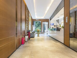 Ein modern gestalteter Hotel-Empfangsbereich mit Rezeption, Sitzgelegenheiten und Blick ins Freie.