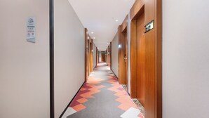 Un pasillo de hotel con alfombra estampada, puertas de madera y un cartel en la pared.