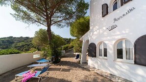 Una villa con patio in ghiaia, arredi esterni e vista sul paesaggio circostante.