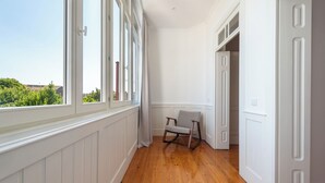 A hallway with wooden flooring, white walls, and a rocking chair. - Bonfim 241 Family House (Porto)