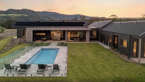 Ein modernes Haus mit Schwimmbad, Sitzgelegenheiten im Freien und Blick auf die Hügel.