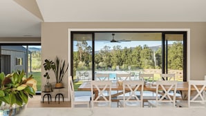 Ein moderner Essbereich mit großem Fenster mit Blick auf Pool und Garten.
