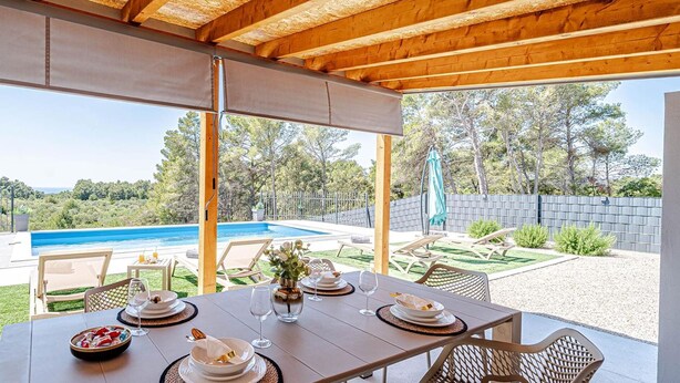 A covered outdoor dining area with a view of a swimming pool and greenery. - Villa Antea by Villas Guide (Vela Luka)
