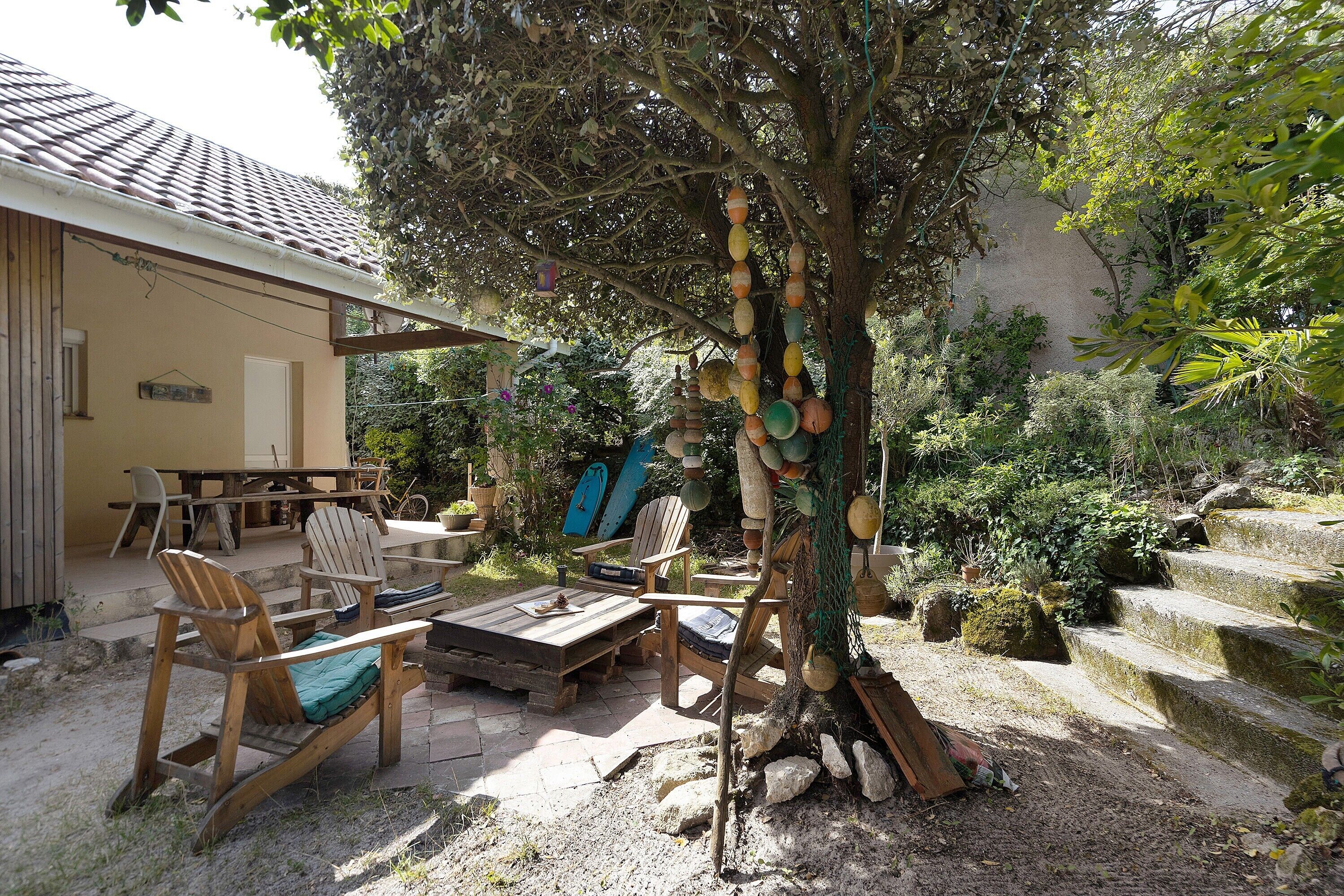 Une terrasse avec des meubles en bois, un arbre décoré de guirlandes et un escalier en pierre.