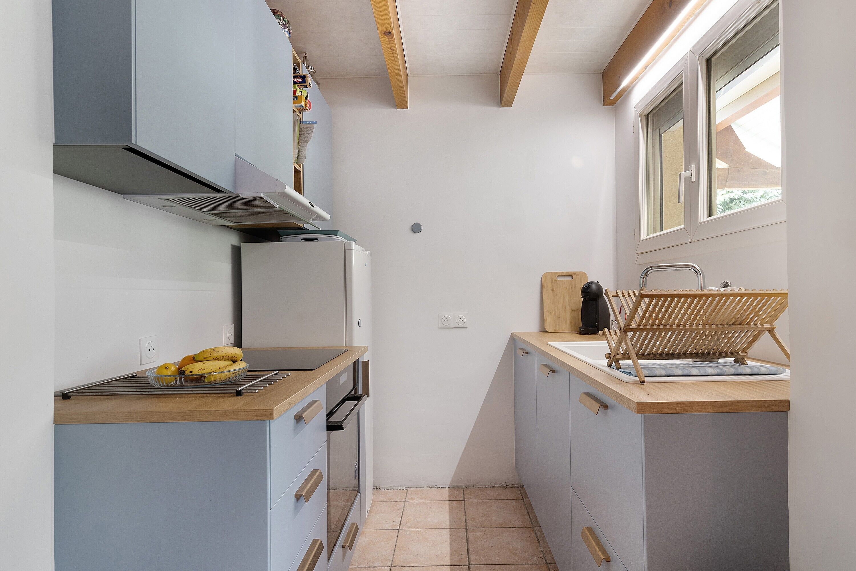A compact kitchen with a built-in oven, a sink, and a window.