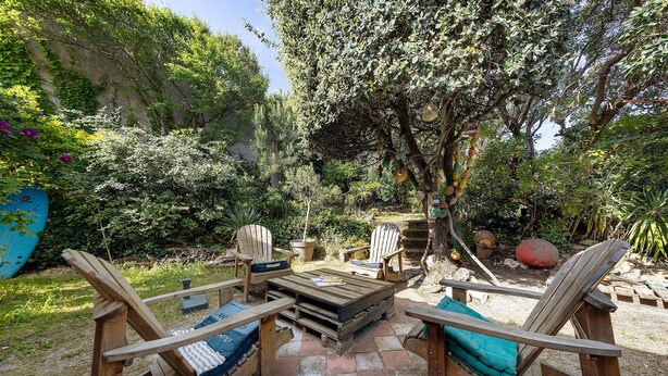 Un patio al aire libre con mobiliario de madera y suelo de piedra.