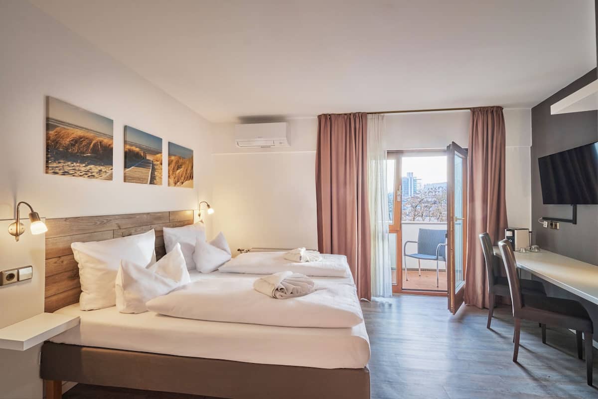 A hotel room with a bed, a desk, and a view of the city.