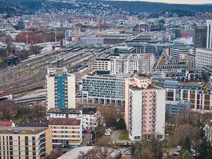 A high-rise building with multiple floors, surrounded by other buildings and a railway station. - Luna Inn (Stuttgart)