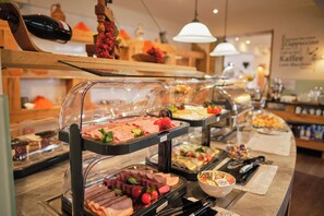 Ein Buffet mit verschiedenen Speisen, darunter Fleisch und Obst, präsentiert in übersichtlichen Behältern.