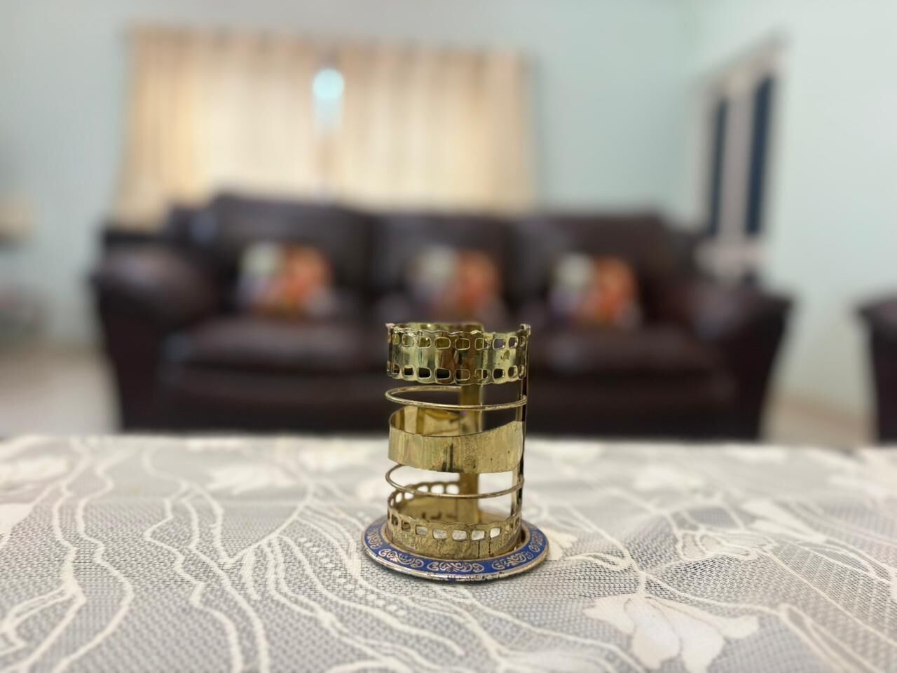 A brass candle holder on a lace tablecloth.