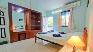 A bedroom with a bed, bedside table with a lamp, a wardrobe, and a window with curtains. - Spring Field Villa (Orlim)