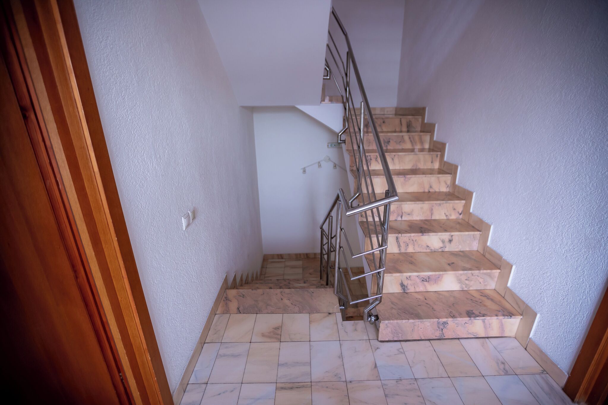 A staircase with wooden steps and metal railings, leading to an upper floor.