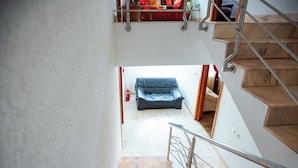 A staircase leading to a lower level with a blue sofa and a fire extinguisher on the floor. - Noroc si Fericire (Târgu Mureș)