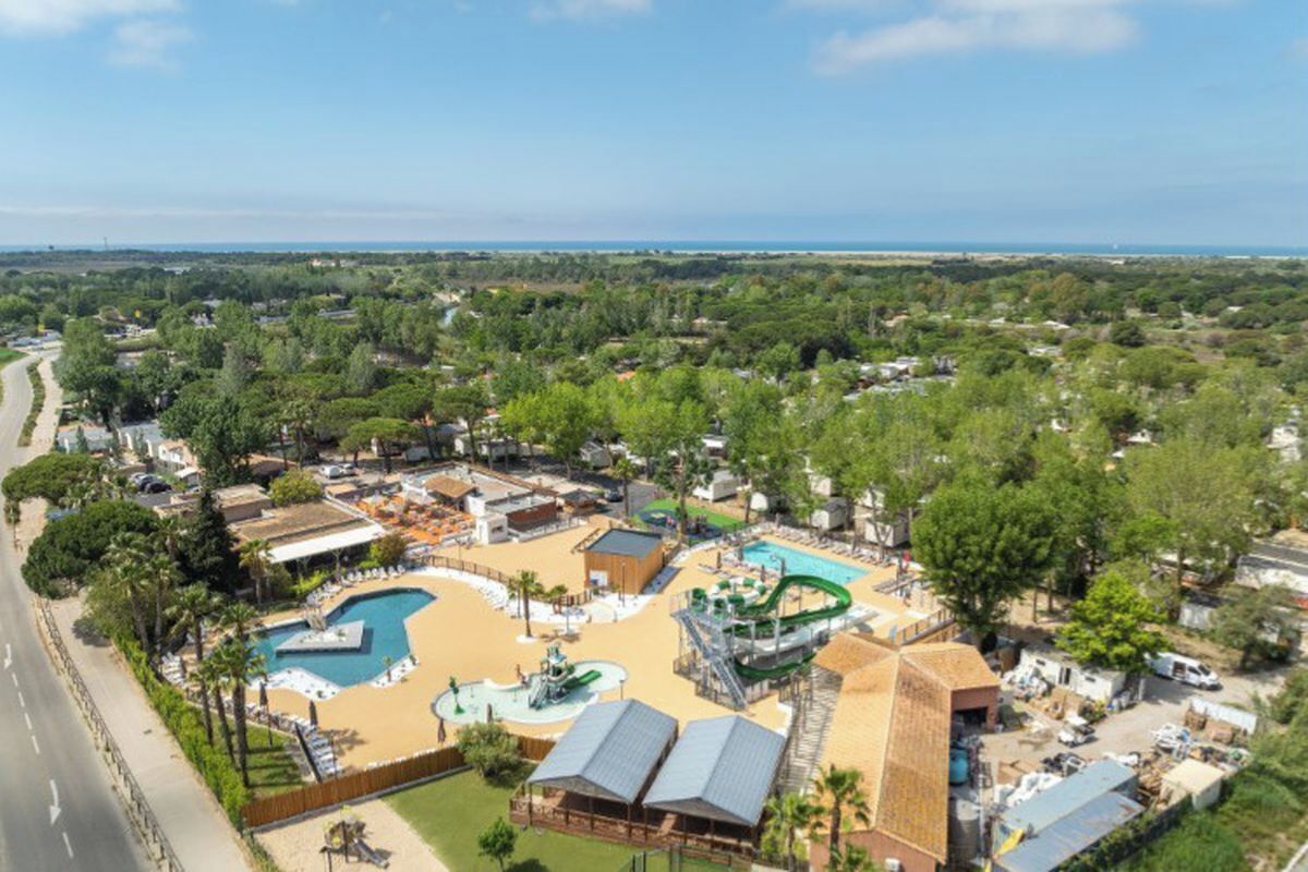 An aerial view of a resort with multiple swimming pools, a water park, and a beach area.