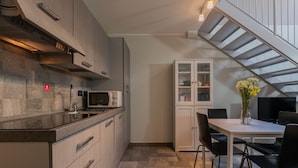A modern kitchen with a microwave, cabinets, and a dining area with a table and chairs. - Loft Tramvai by Wonderful Italy (Turin)