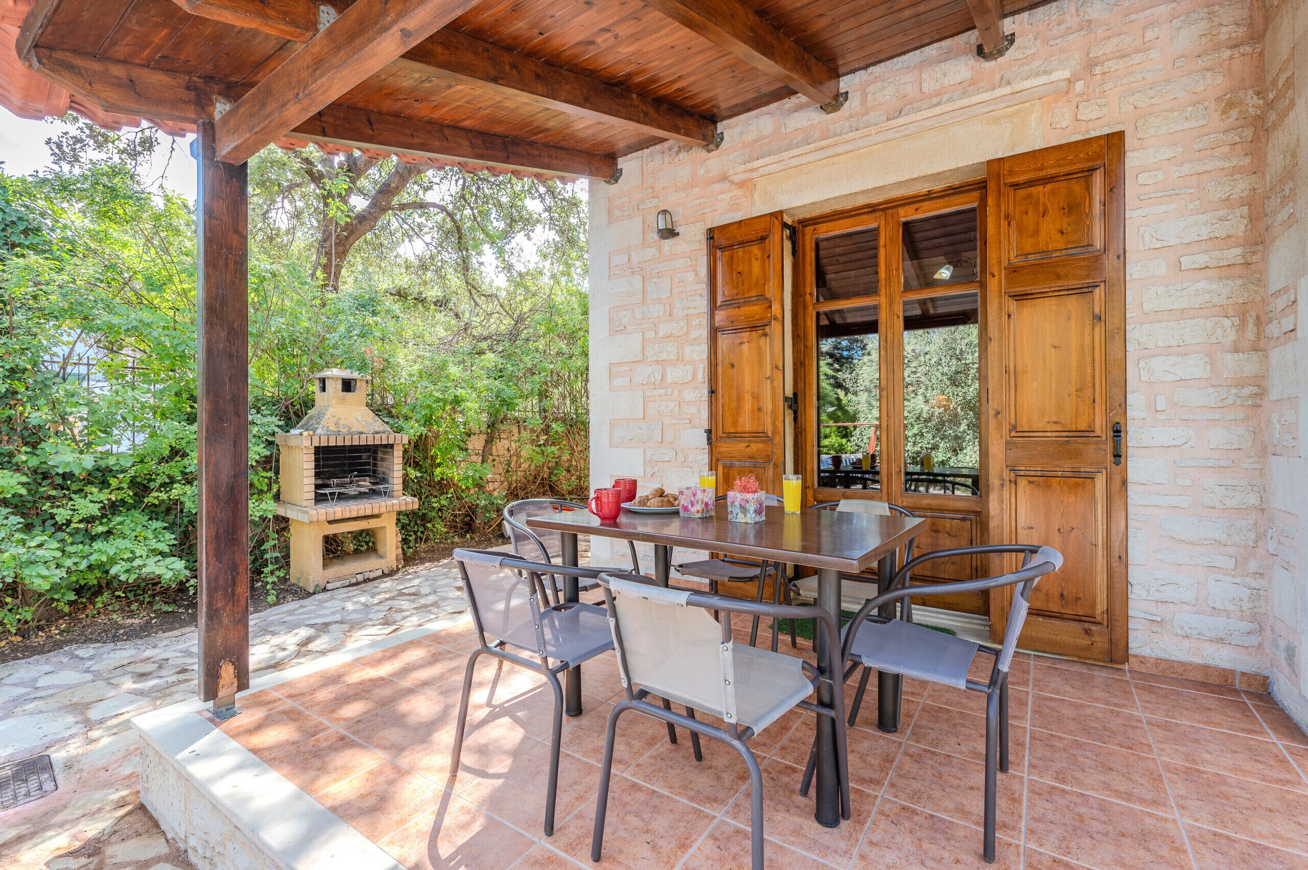 Une terrasse extérieure avec un mur en pierre, une porte en bois et un four en briques.