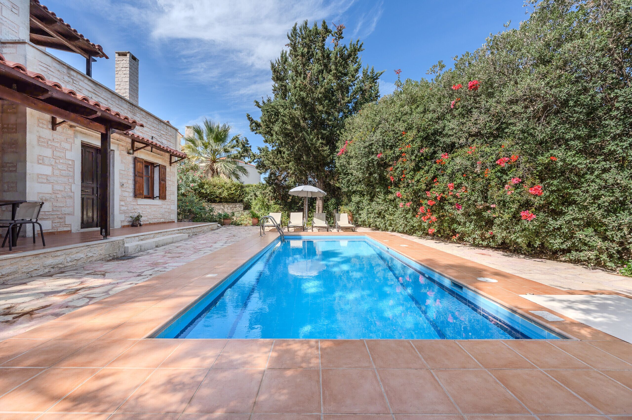 A swimming pool with a stone house and garden.