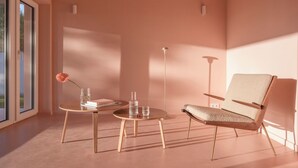 A modern room with a large window, a round wooden table, a beige chair, and a vase with a rose. - Award-Winning, Magazine-Featured, Architect-Designed Lakeside Home (Vitnyéd)