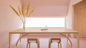 A minimalist room with a wooden table and two chairs, a vase with yellow flowers, and a large window providing natural light. - Award-Winning, Magazine-Featured, Architect-Designed Lakeside Home (Vitnyéd)