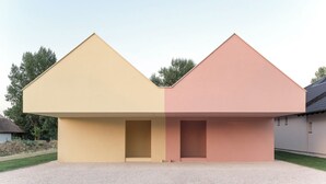 A modern building with two distinct sections, one yellow and one pink, featuring a flat roof and a gravel driveway. - Award-Winning, Magazine-Featured, Architect-Designed Lakeside Home (Vitnyéd)
