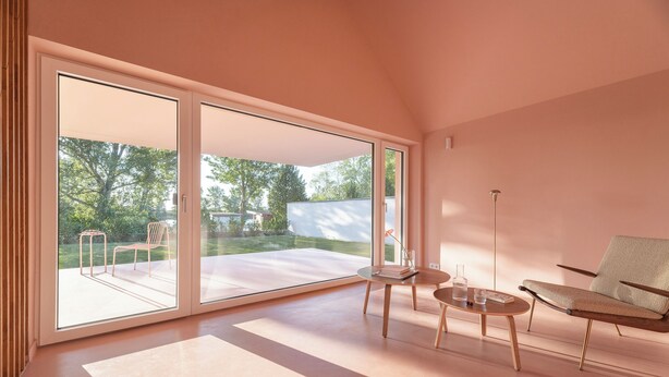 A spacious room with large sliding glass doors leading to a patio, a round wooden table with chairs, and a modern armchair. - Award-Winning, Magazine-Featured, Architect-Designed Lakeside Home (Vitnyéd)