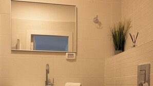 A modern bathroom with a wooden vanity, a mirror, a toilet, and a small plant. - LOUI TALPIOT HOTEL: Authentic Experience. Art, Market,Rooftop & Boutique Comfort (Haifa)