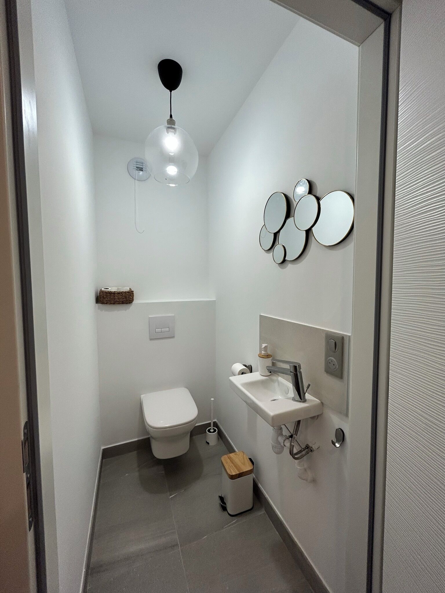 Un baño moderno con inodoro, lavamanos y espejos decorativos.