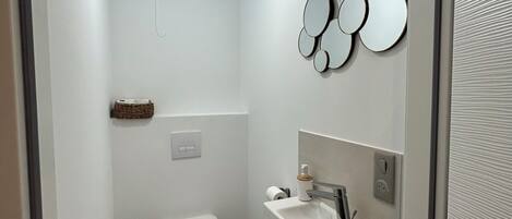 Un baño moderno con inodoro, lavamanos y espejos decorativos.
