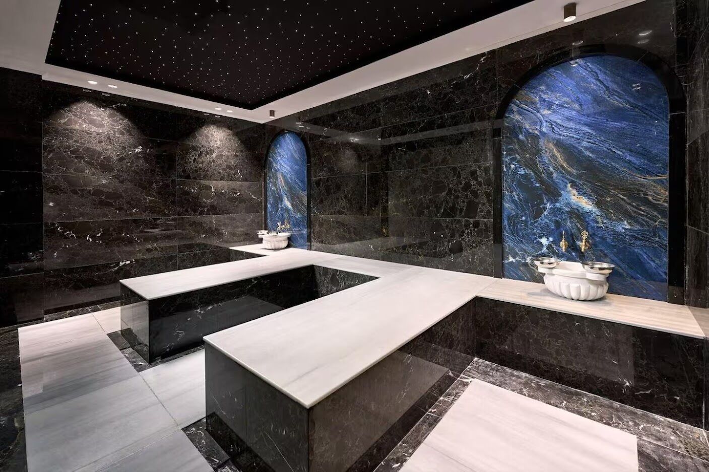 Un baño moderno con piso de mármol, un lavamanos grande y un techo con estrellas.