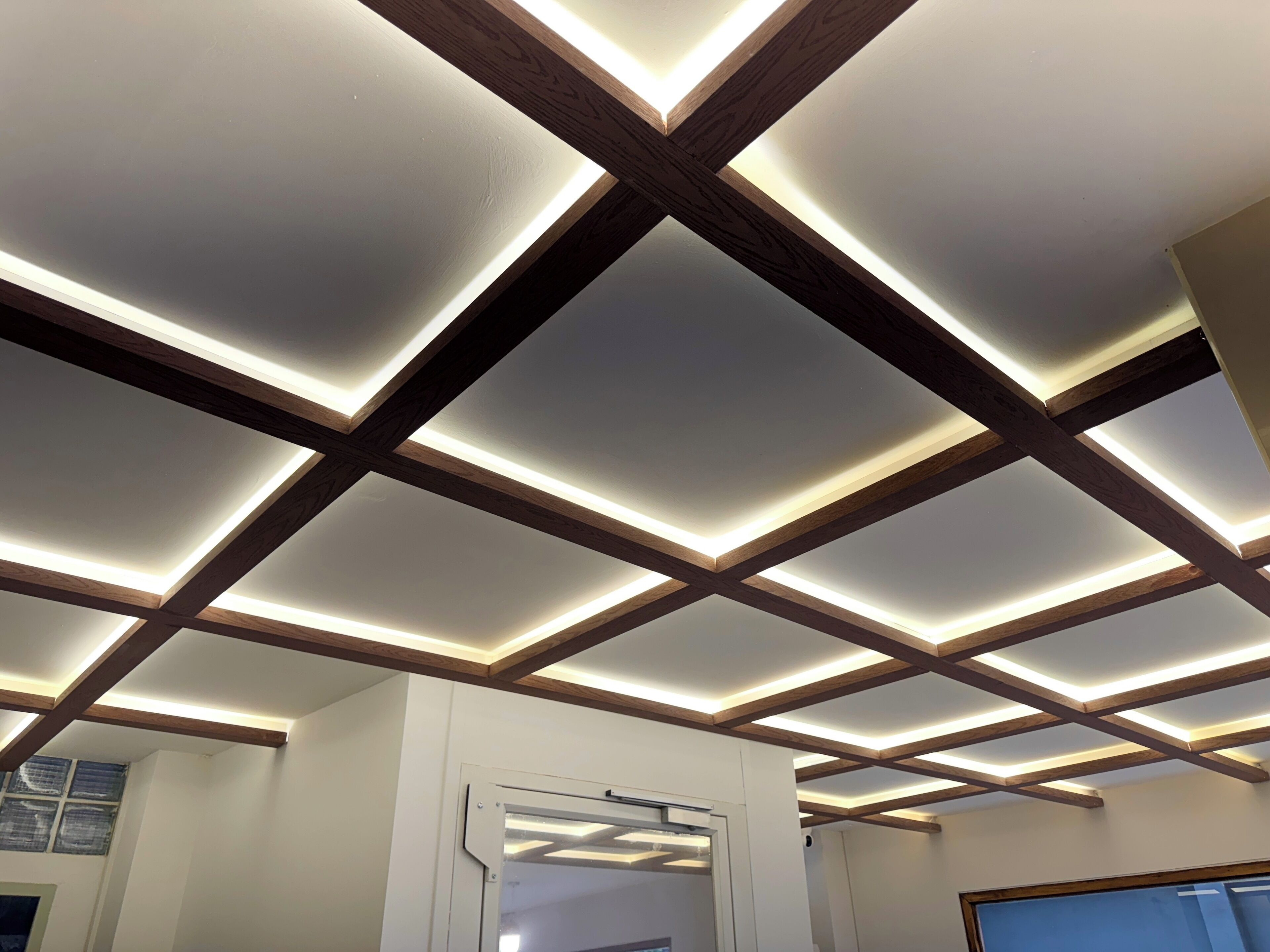 Un plafond avec des poutres en bois et des spots encastrés.