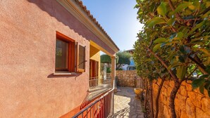 A building with a stone wall, a balcony with a metal railing, and a stone pathway. - Holiday Home 'Trilocale Luana' with Sea View, Shared Pool and Air Conditioning (Maiorca)