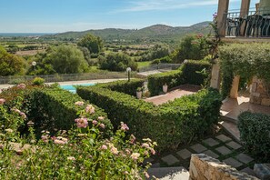 A landscaped garden with a pool, stone pathway, and a view of the countryside. - Holiday Home 'Trilocale Luana' with Sea View, Shared Pool and Air Conditioning (Maiorca)