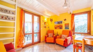 A bright room with orange walls, a wooden ceiling, and a dining area with a table and chairs. - Holiday Home 'Trilocale Luana' with Sea View, Shared Pool and Air Conditioning (Maiorca)