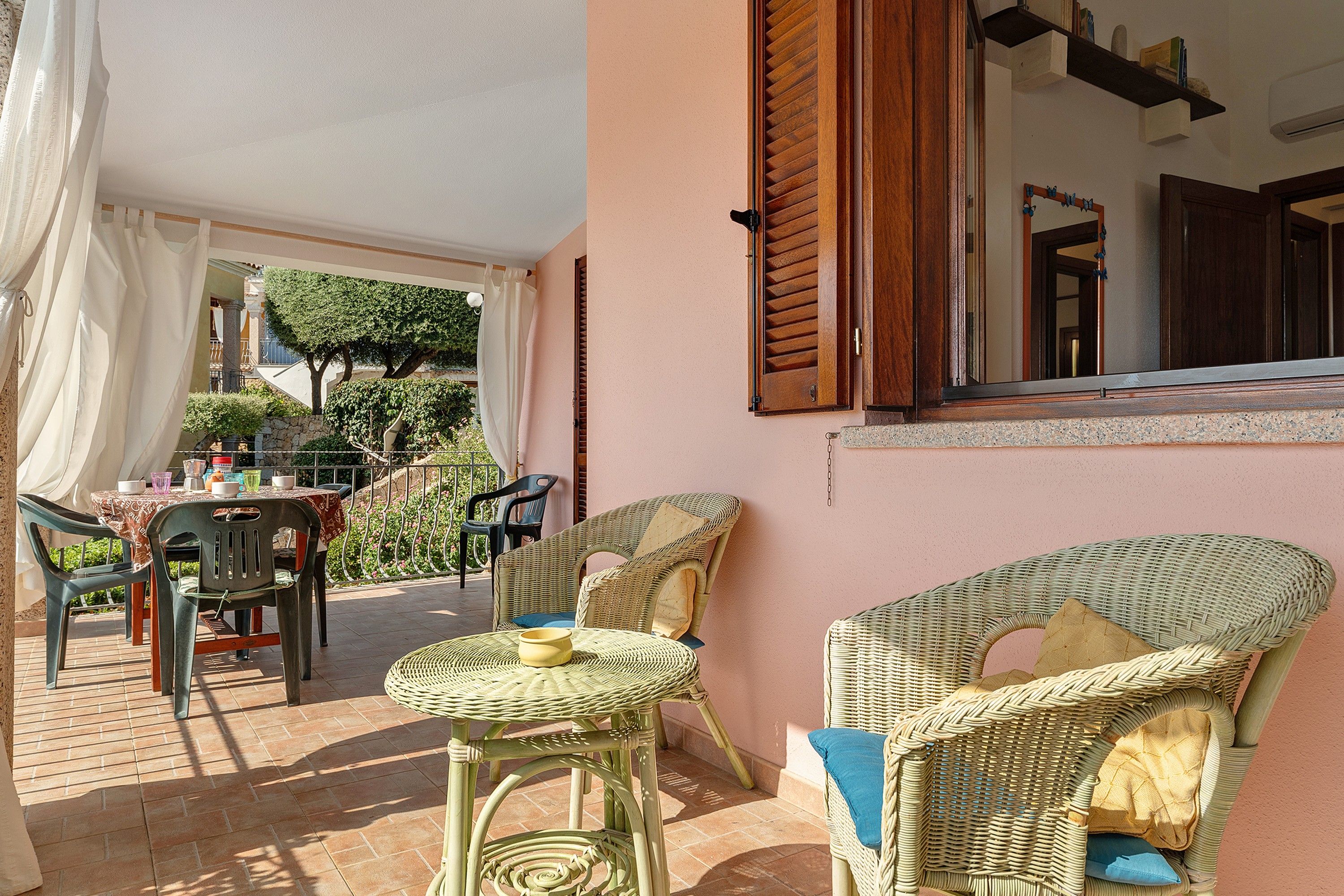 Ein Terrassenbereich im Freien mit Korbmöbeln, einem Tisch und Stühlen.