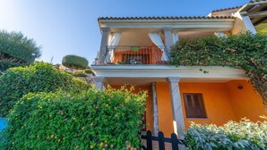 A two-story building with a balcony, surrounded by lush greenery. - Holiday Home 'Trilocale Luana' with Sea View, Shared Pool and Air Conditioning (Maiorca)