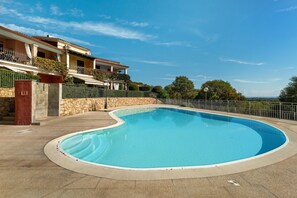 A swimming pool with a curved edge, surrounded by a stone wall and a metal fence. - Holiday Home 'Trilocale Luana' with Sea View, Shared Pool and Air Conditioning (Maiorca)