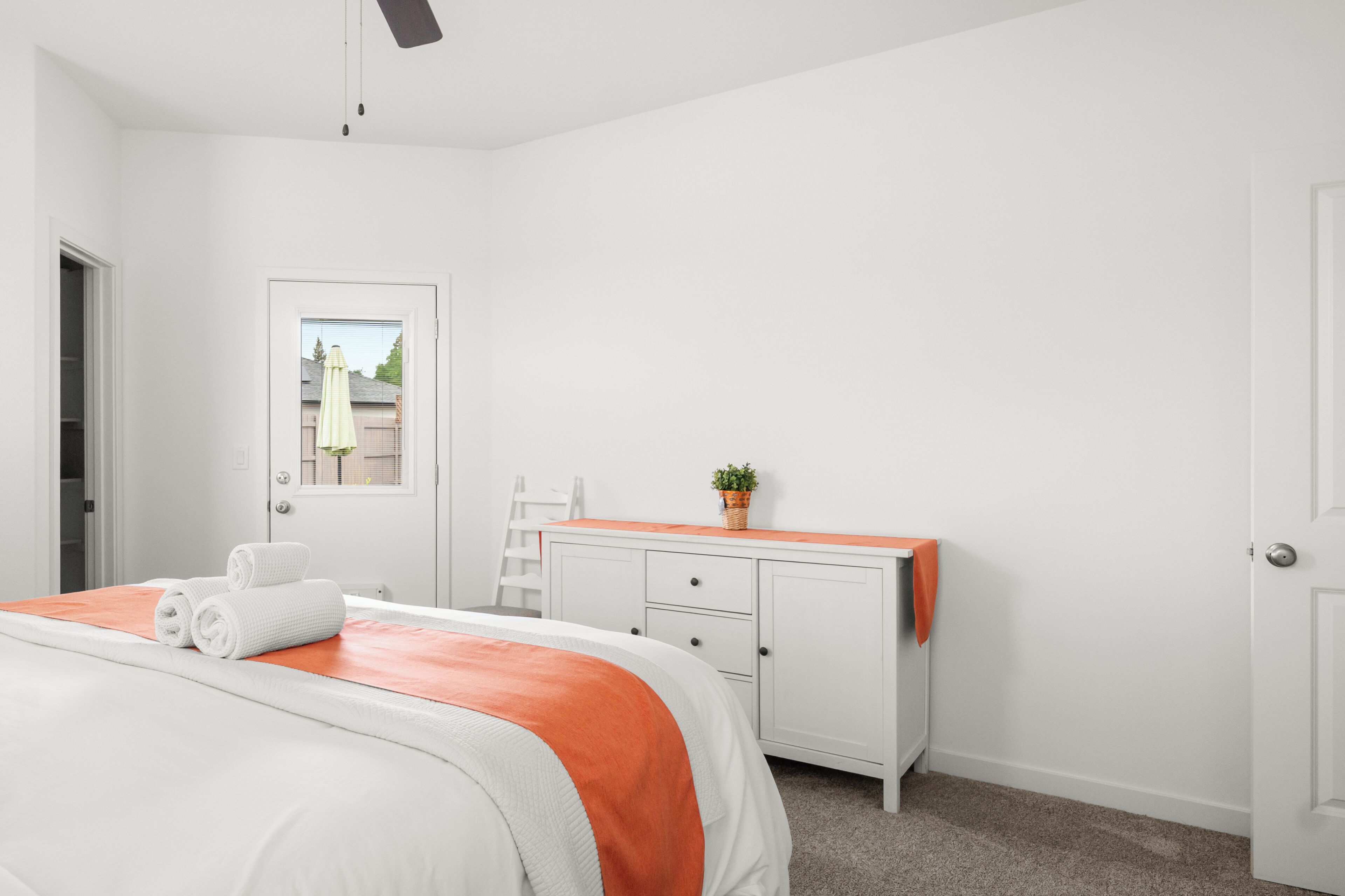 A bedroom with a bed, a dresser, a window, and a door.