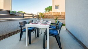 A small outdoor patio with a white table and black chairs, surrounded by a low wall and a wooden fence. - Apartman Sabina 2 by Villas Guide (Fažana)