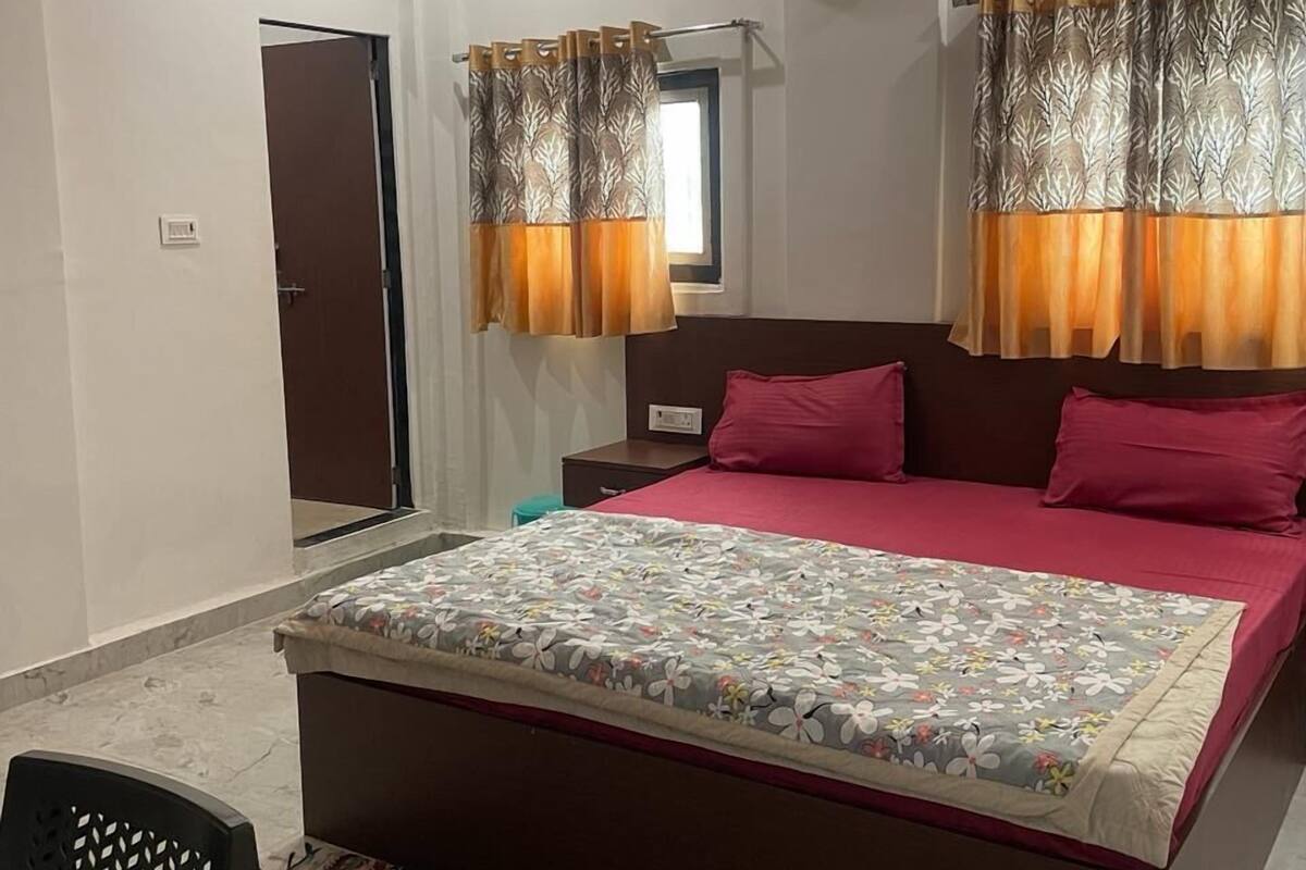 Une chambre à coucher avec un lit, un ventilateur de plafond, un appareil de climatisation et une fenêtre avec des rideaux.