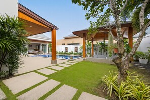 A modern outdoor area with a swimming pool, covered seating, and a well-maintained lawn. - Villa Hemi 2BR Modern Thai Style (Choeng Thale)