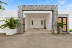 A modern building entrance with a stone facade, a concrete floor, and potted plants. - Villa Hemi 2BR Modern Thai Style (Choeng Thale)