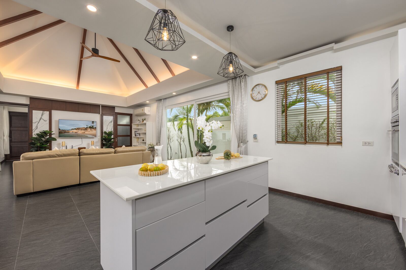 A modern kitchen with a central island, a dining area with a sofa, and a living room with a TV.