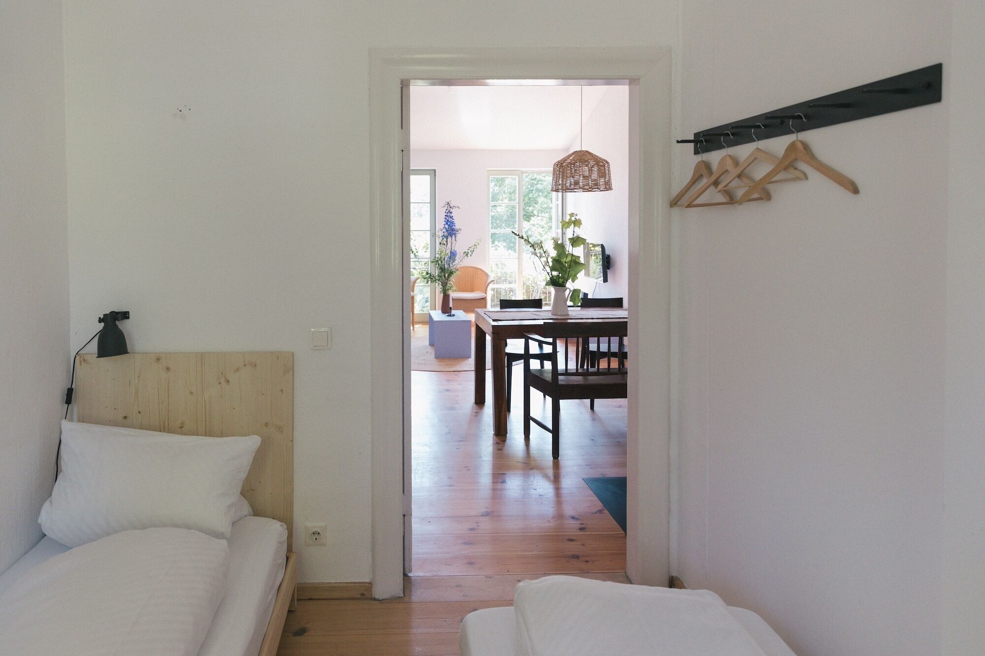Una habitación con una cama de madera, una mesa de comedor con sillas y un perchero.